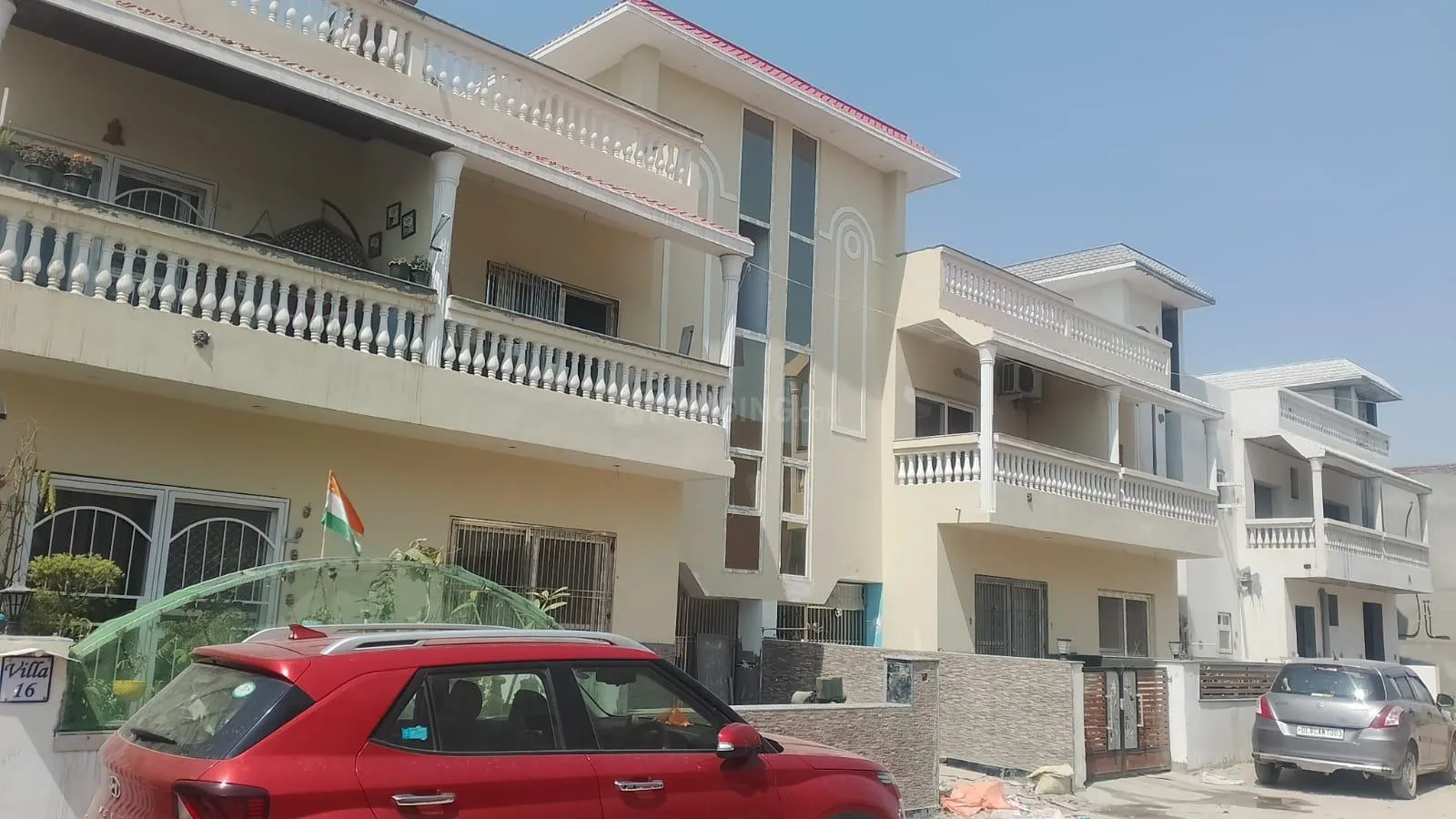 Aroma Luxury Prime Villa — Row of light cream colored villas with balconies and a red car parked in front.